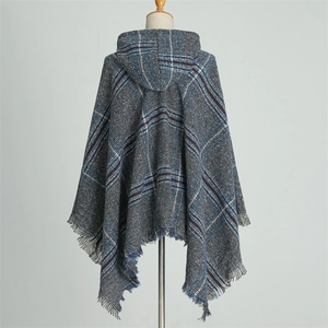 Detail of blue plaid knitted hooded poncho featuring fringe hem on a studio mannequin