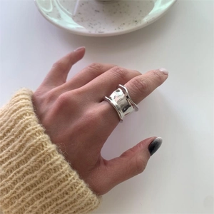 Close-up of irregular wide-surface silver ring worn on hand with cozy knitwear background