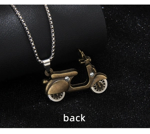 Macro side view of vintage bronze scooter pendant with intricate metallic details and box chain