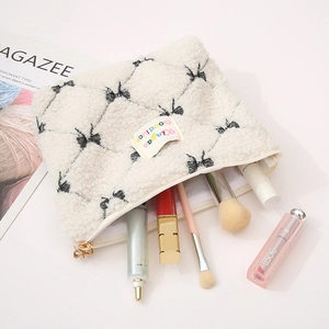 White faux shearling makeup bag with black bow print and golden zipper handle
