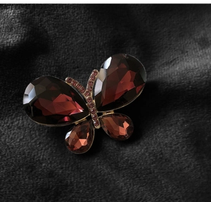 Macro detail of deep red crystal butterfly brooch with gold alloy base and faceted gems