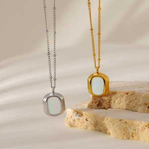 Macro shot of oval white mother of pearl pendant on elegant gold bead chain necklace
