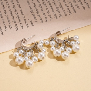 Vintage C-shaped silver earrings with cascading imitation pearls on a book background