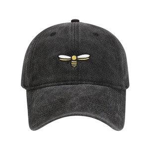 Detailed view of yellow bee embroidery on washed charcoal grey vintage baseball cap