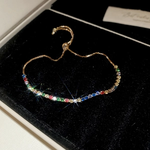 Detail of adjustable gold-tone bracelet with vibrant rainbow crystals on velvet