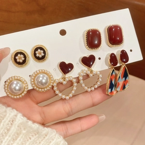 Close-up of vintage resin earrings set with pearls and heart designs on a display card