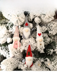 Set of four knitted Christmas gnome ornaments hanging on a snowy holiday tree branch