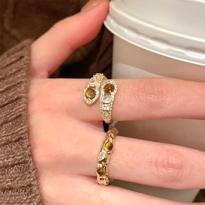 Detail of stacked tiger eye gold rings on finger with elegant zircon embellishments