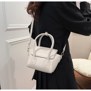 Mini white leather bucket bag with top handles and adjustable strap on a model
