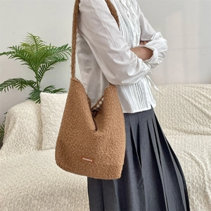 Detail of soft brown fleece crossbody bag showing the leather logo and plush texture