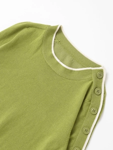 Detail of green knit top featuring shoulder buttons and a white contrast collar neck
