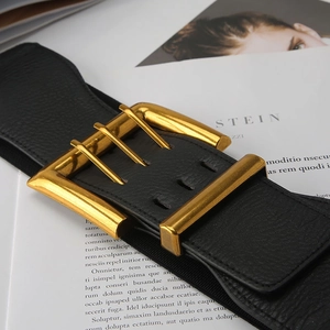 Detail of a wide black elastic waist belt with a textured faux leather gold square buckle