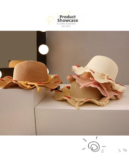 Detail of girl's straw hats with cherry embroidery and wavy edges in multiple colors
