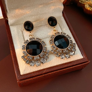 Détail de boucles d'oreilles vintage fleurs avec gemmes noires et cristaux dans un coffret