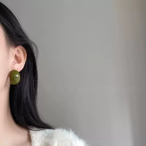 Olive green acrylic C-shape stud earring worn by a model in a minimalist style