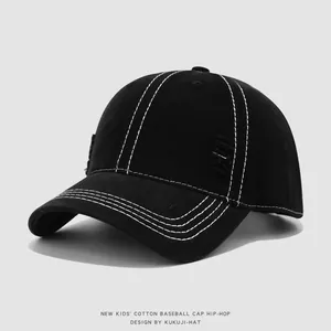 Detalle de gorra infantil negra con costuras blancas en contraste y bordes desgastados