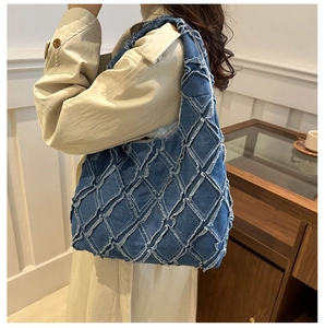 Detail of blue denim tote bag featuring frayed edges and diamond quilted stitching pattern