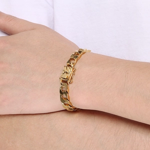 Detail of a gold Cuban link chain bracelet worn on a wrist with textured metal clasp