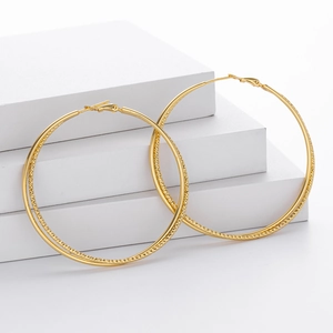 Detail shot of large S925 silver hoop earrings with a shiny diamond-cut texture pattern