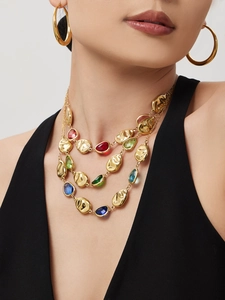 Detail view of multi-layered gold necklace with colorful teardrop stones and hammered metal