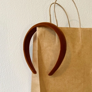 Detail of caramel velvet headband on a paper bag showing soft texture and rich color