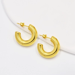 Macro shot of polished gold-finished C-shaped hoop earrings with a smooth surface