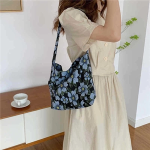 Detail of floral jacquard pattern on black shoulder bag with blue embroidery accents
