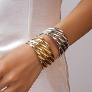 Macro shot of gold and silver metallic bangles with artistic wavy textures on a model wrist
