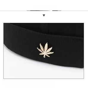 Close-up of golden leaf metal pin on black brimless docker cap with twill texture