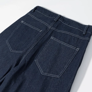 Détail macro de la taille arrière du jean bleu foncé avec surpiqûres blanches contrastées