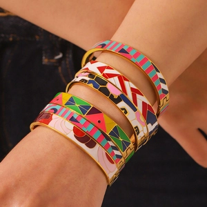 Close-up of colorful enamel 18k gold plated bangles with geometric patterns on denim fabric