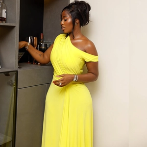 Detail of the bright yellow one-shoulder maxi dress showing silky pleated fabric texture