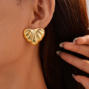 Close-up of golden heart earrings with shell texture on model showing elegant fit
