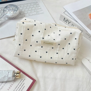 Lifestyle shot of white striped cosmetic bag with heart print on an organized desk