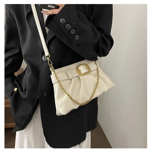 Détail d'un sac bandoulière plissé blanc crème avec grande boucle dorée et chaîne