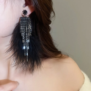 Macro shot of black tassel earrings with feathers and beads on ear, gothic style