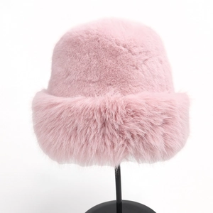 Detailed close-up of a cozy pink faux fur winter bucket hat on a black display stand