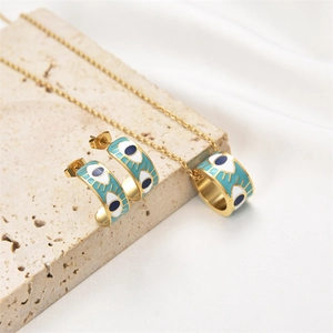 Detail of gold evil eye jewelry set featuring enamel earrings and cylindrical necklace