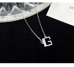 Macro detail of S925 silver letter G pendant with sparkling cubic zirconia inlay
