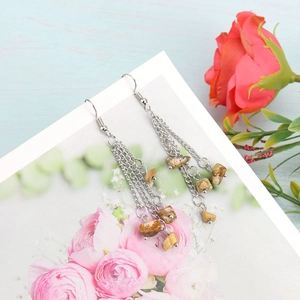 Detail of bohemian tassel earrings with natural brown stone chips and silver chains