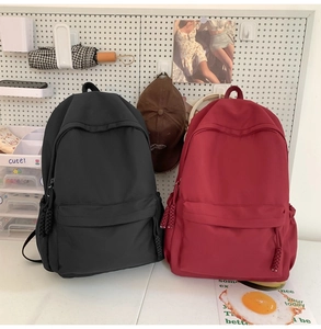 Minimalistische schwarze und rote Nylon-Rucksäcke auf einer weißen Lochplatte