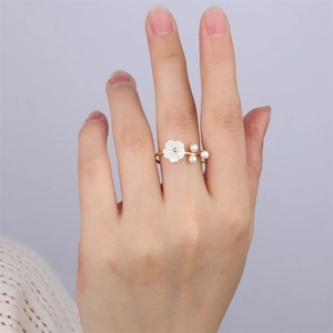 Gros plan d'une bague fleur dorée avec trois perles portée par un mannequin
