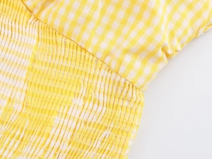 Detail of yellow gingham fabric featuring elastic smocking and pleated texture