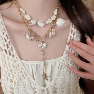 Close-up of bohemian layered gold necklace with pearls, seashells and starfish charms