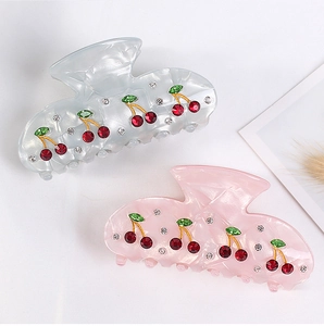 Detail view of acrylic hair claws with cherry rhinestones in light blue and pink tones
