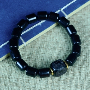 Bracelet en perles de bois de santal avec breloque gravée et accents dorés sur tissu rétro