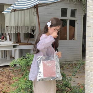Detail of silver sequin tote bag featuring pink suede pocket and stylish rope handle