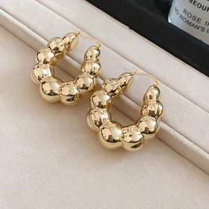 Macro shot of chunky golden bubble hoop earrings featuring a high-polish mirror finish