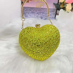 Macro detail of yellow rhinestone heart-shaped evening bag with golden metal handle