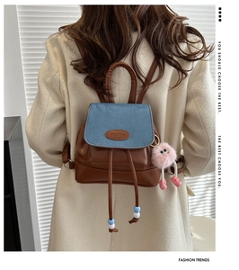 Mini zaino in pelle marrone e denim con ciondolo rosa su modella, vista posteriore